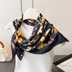 Detail of navy blue satin silk scarf with yellow floral print on a white rib top