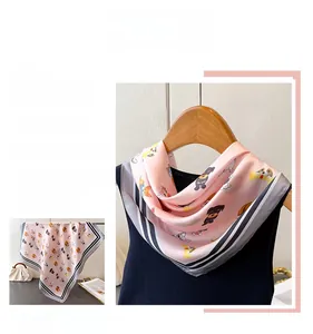 Détail d'un foulard en soie rose avec motifs de chiots et bordure rayée noire et blanche