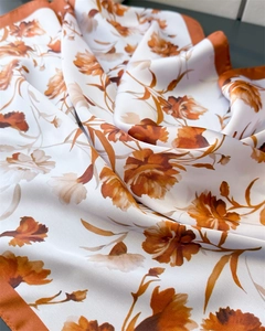 Detailed view of satin floral scarf with orange and brown flower patterns and smooth texture