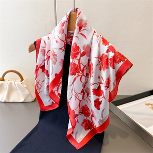 Floral satin silk scarf with red flower patterns on creamy white background draped on a hanger