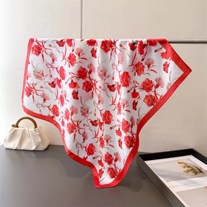 Detail of red floral satin scarf draped on a metal rack showing its silky texture