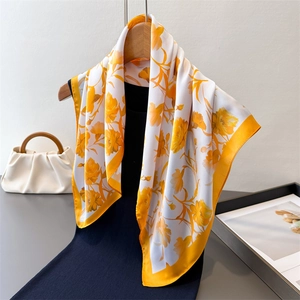Floral satin silk scarf in vibrant yellow and white draped over a black dress