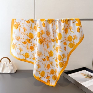 Detailed view of yellow floral pattern on elegant satin silk scarf with soft drape