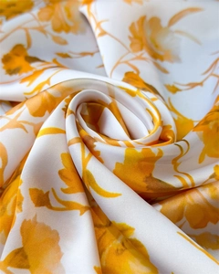 Macro detail of silky satin scarf with bright yellow floral patterns and smooth texture