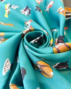 Gros plan d'un foulard en soie sarcelle avec imprimés chiens en spirale satinée