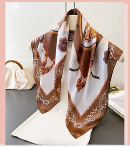 Détail d'un foulard en soie avec des motifs de chaînes dorées et de glands sur blanc