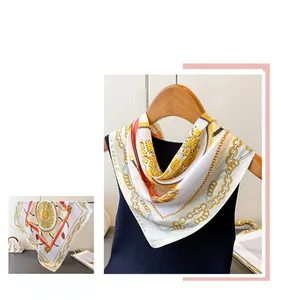 Détails d'un foulard en soie de luxe avec motifs de chaînes dorées et lignes rouges