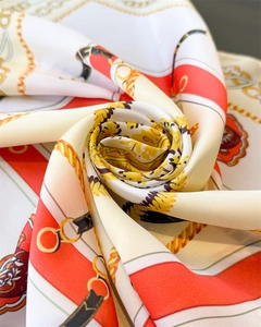 Détail d'un foulard en soie de luxe avec motifs de chaînes orange et or en pli élégant