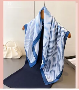 Close-up of blue and white printed silk scarf with abstract patterns and solid navy borders