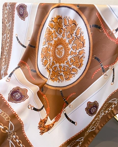 Vue détaillée d'un foulard en soie avec motifs baroques et chaînes équestres dorées