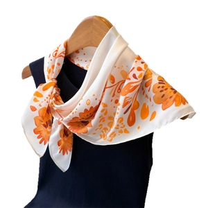 Eleganter Seidenschal mit orangefarbenem Blumenmuster auf Creme am Holzbügel aufgehängt