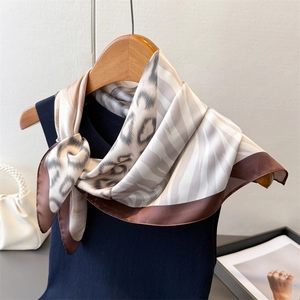 Elegant animal print silk scarf with leopard and zebra patterns on a wooden hanger