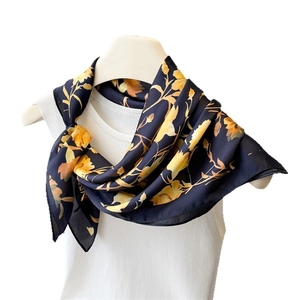 Navy blue floral satin scarf with yellow blossoms elegantly tied on a white mannequin