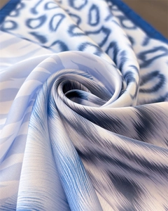 Detailed view of the silky blue and white animal print scarf with a smooth satin texture