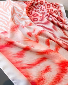 Close-up of elegant silk scarf showing animal print patterns and smooth satin texture