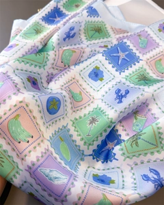 Close-up of lightweight satin scarf featuring tropical marine stamps and starfish patterns