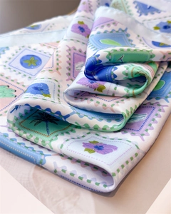Detailed view of floral stamp print on silk scarf with soft folds and elegant sheen