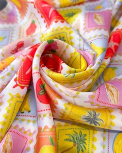 Detailed view of silky satin scarf fabric with tropical fruit and seashell stamp patterns