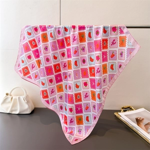 Detailed view of square silk scarf featuring colorful tropical stamps and pink stitched edges