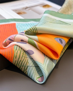 Nahaufnahme des Seidenschals mit orange-grünen abstrakten Mustern und Satin-Textur
