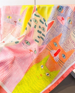 Detail eines Seidenschals mit Katzenprint zeigt glatte Textur und bunte Stoffe
