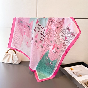 Detail eines Seidenschals mit Katzenprint und leuchtend pinkem Rand am Kleiderbügel
