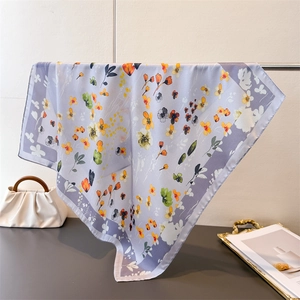 Elegant lavender silk scarf with floral print and purple borders displayed on a rack