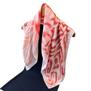 Elegant red and white feather print faux silk scarf displayed on a wooden hanger