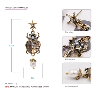 Vintage beetle drop earrings with pearls and rhinestones on a white background