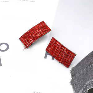 Detail of red rhinestone hair clips on a magazine, showing luxury metal craft