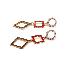 Close-up of geometric gold earrings with pink and red crystals in circular and square shapes
