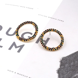 Boucles d'oreilles créoles dorées ornées de strass multicolores sur fond de papier glacé