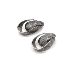Macro detail of retro silver teardrop earrings with textured grain and rhinestone accents