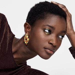 Luxurious gold textured earrings with colorful rhinestones on a fashion model