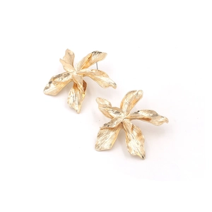 Détail macro de boucles d'oreilles fleurs dorées avec pétales 3D et finition mate texturée