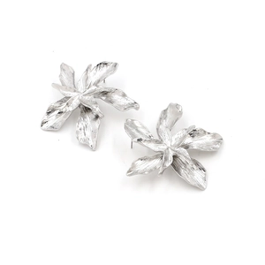 Vue détaillée de boucles d'oreilles fleur argentée avec pétales texturés et métal