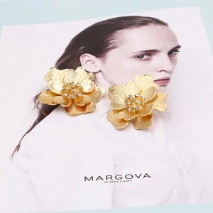 Vintage golden floral stud earrings with sparkling rhinestones on artistic model card