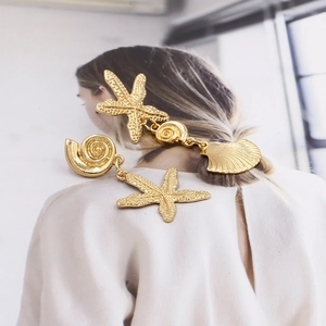 Gold starfish and seashell drop earrings featuring textured metallic marine design