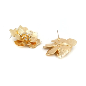 Macro detail of golden flower earrings showing brushed texture and crystal center