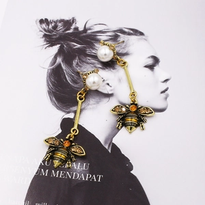 Vintage gold bee drop earrings with pearls and amber rhinestones on a white background
