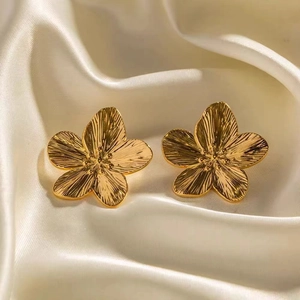 Gros plan de boucles d'oreilles fleurs plaquées or 18K avec textures de pétales sur satin