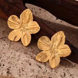 Vue macro de boucles d'oreilles fleuries plaquées or 18 carats avec texture brossée