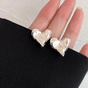 Details von silbernen Herzohrringen mit einer einzigartigen Knitteroptik-Metalloberfläche