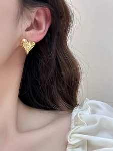 Detailansicht der goldenen Herz-Ohrstecker mit Lavatextur getragen am Modellohr