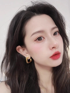 Close-up of elegant gold heart earrings on model showing glossy metallic finish