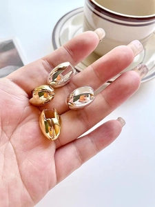 Detailed view of polished egg-shaped hoop earrings in gold and silver finishes
