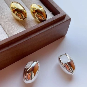 Polished chunky teardrop earrings in gold and silver finish shown on jewelry display