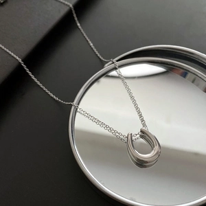 Minimalist silver horseshoe pendant necklace in polished titanium steel on mirror