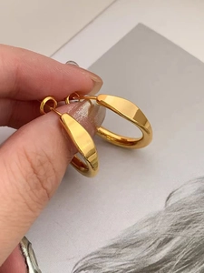 Nahaufnahme klobiger goldener Creolen, handgehalten für metallischen Glanz und Größe