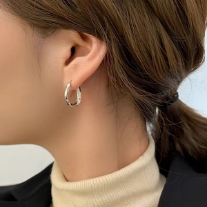 Minimalist silver geometric U-shaped hoop earrings on model with sleek metallic finish